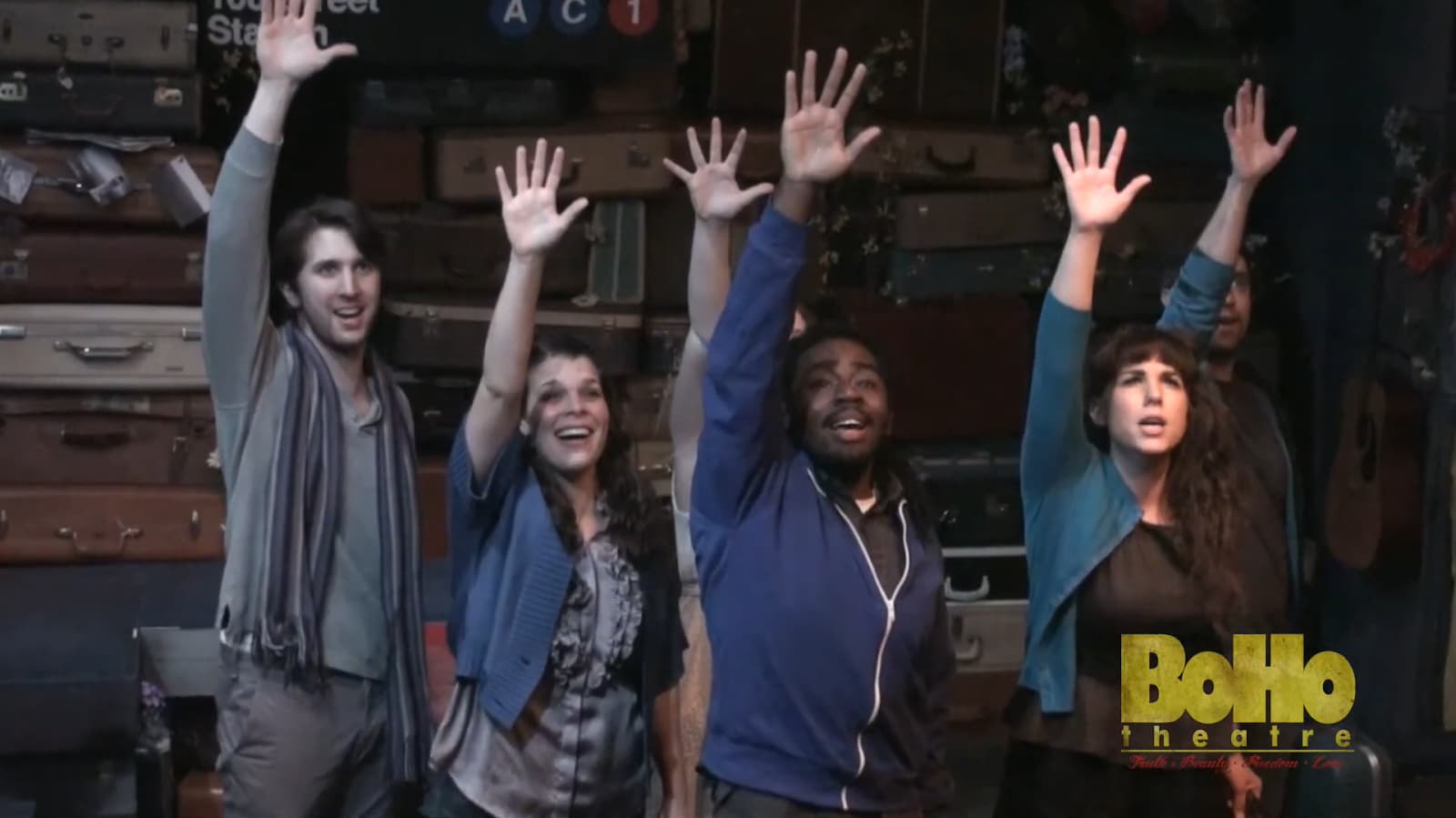 A jubilant cast raises their hands on stage at Boho Theatre